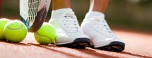 Legs of athlete near the tennis racket and balls